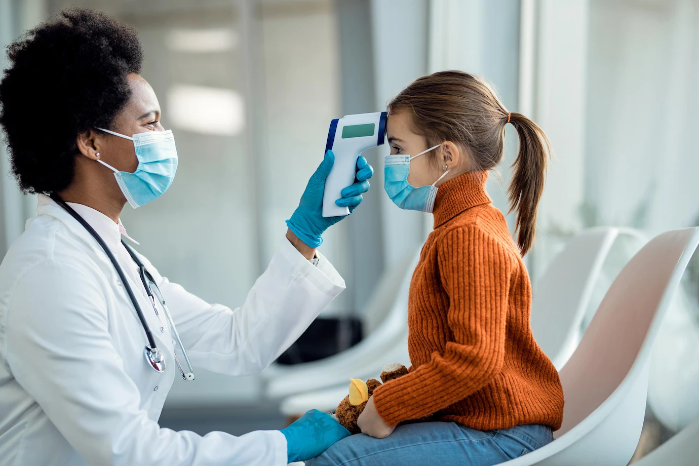 african-american-doctor-measuring-temperature-small-girl-waiting-room-clinic_637285-11222