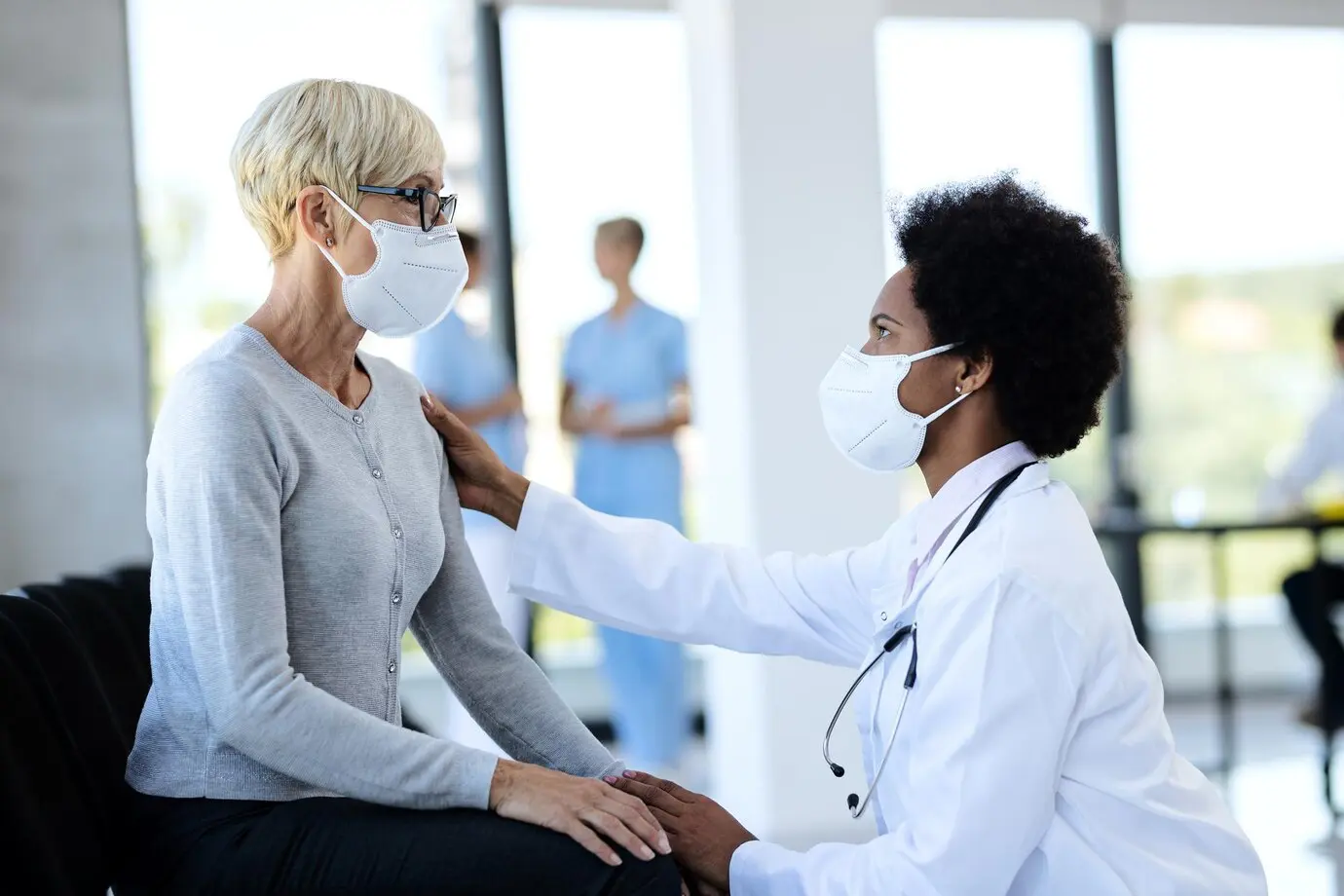 black-doctor-mature-patient-wearing-protective-face-masks-while-talking-waiting-room-clinic_637285-9078